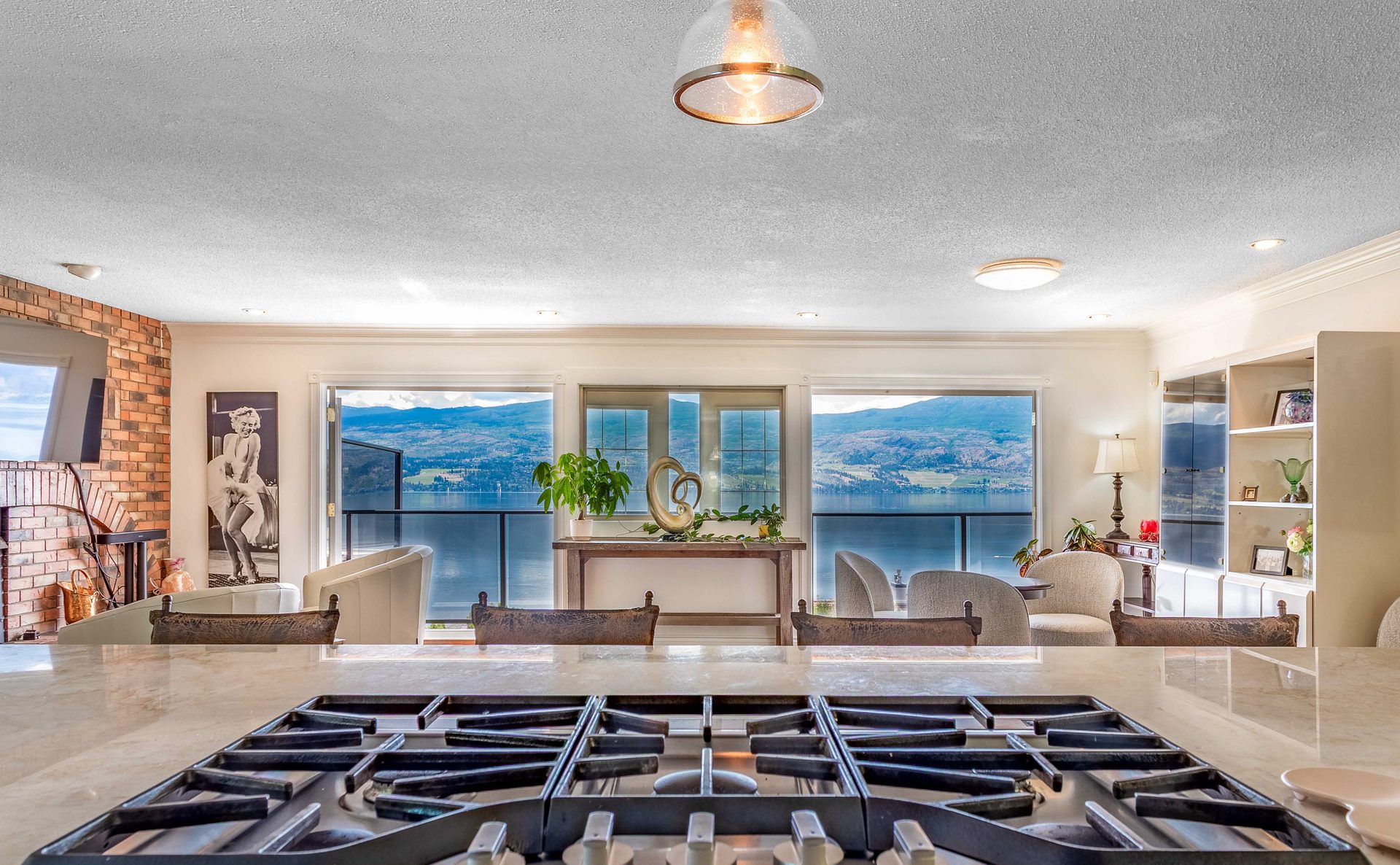 View from kitchen island over gas cooktop toward Okanagan Lake through panoramic windows
