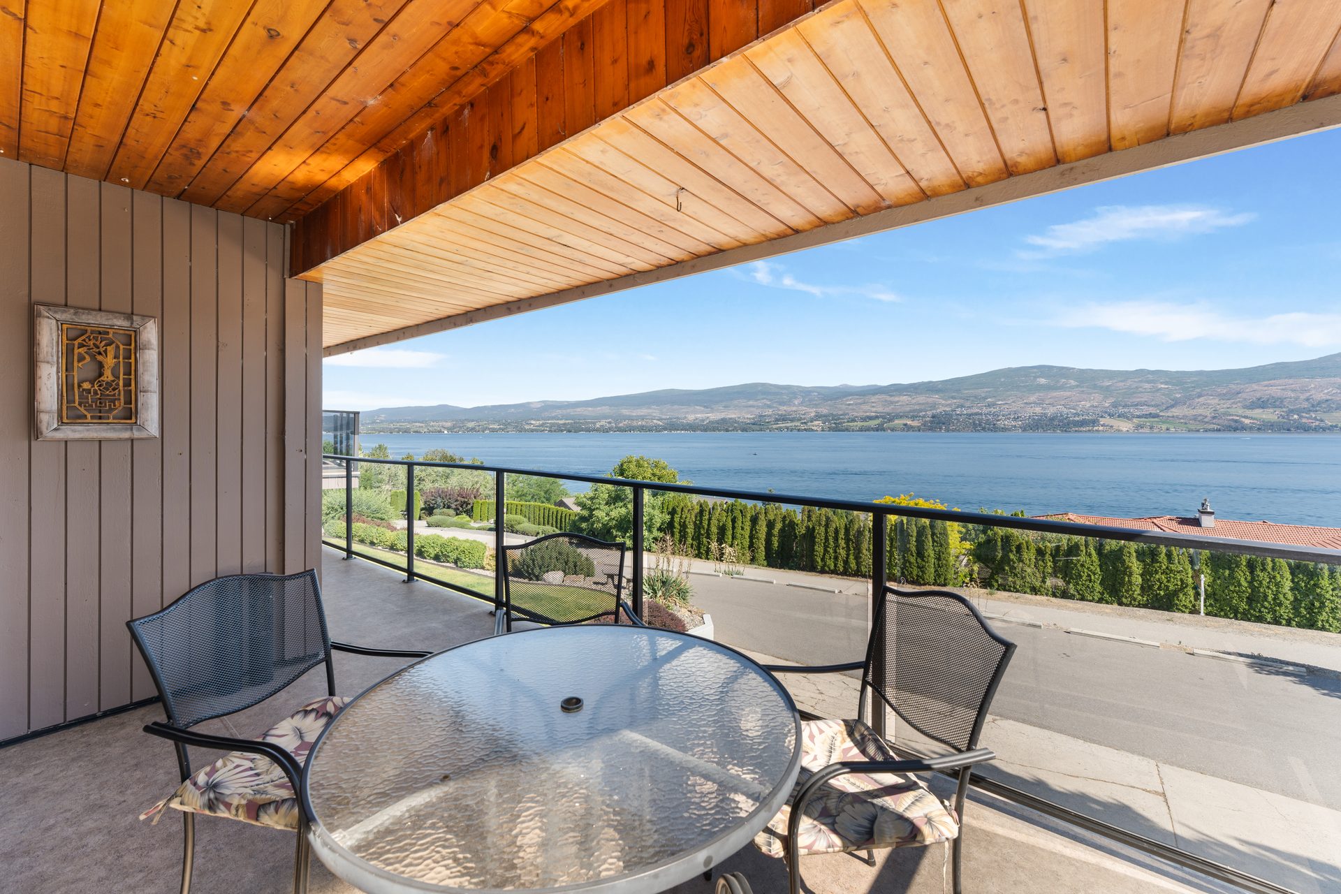 Upper balcony bench with panoramic Okanagan Lake view and landscaped grounds below