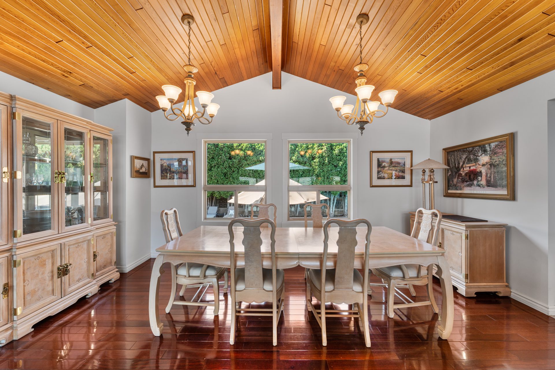 Formal dining room with vaulted cedar ceiling, twin chandeliers, eight-seat table and china cabinet