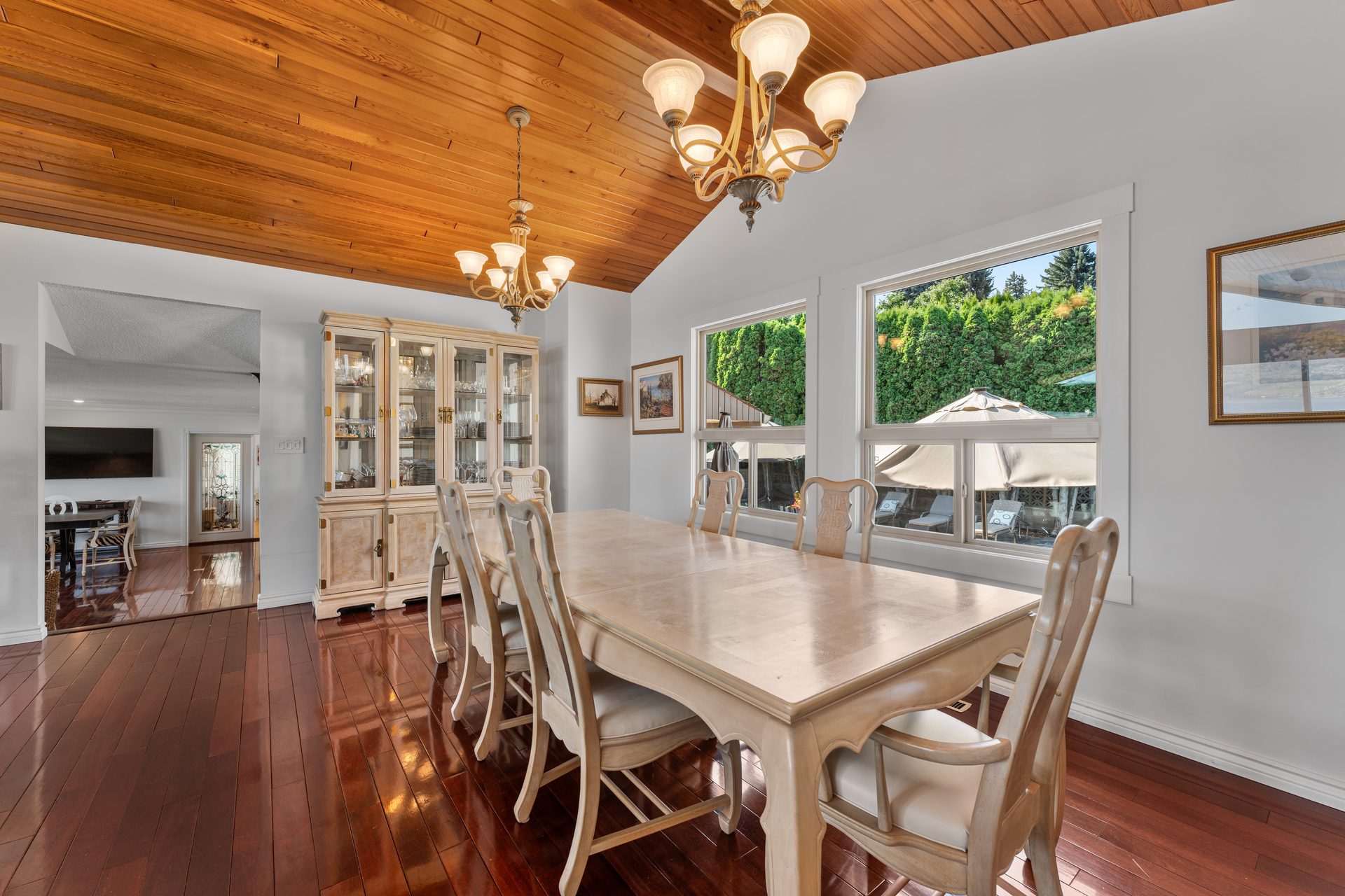 Formal dining room second angle showing cedar ceiling, chandeliers and pool view through windows