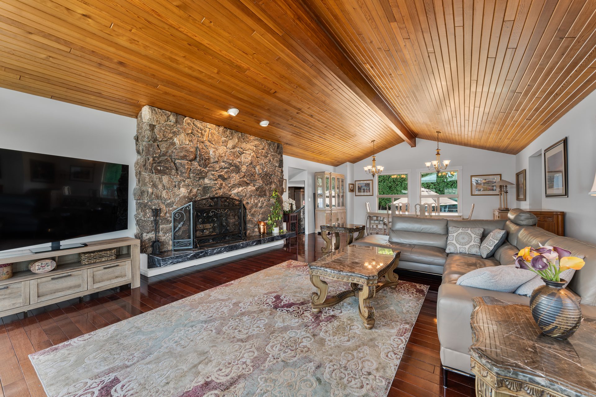 Great room from fireplace wall angle showing cedar ceiling, sectional sofa and view through to formal dining